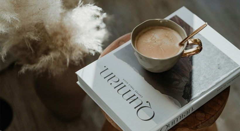 a coffee sitting on a book on a stool in a living room